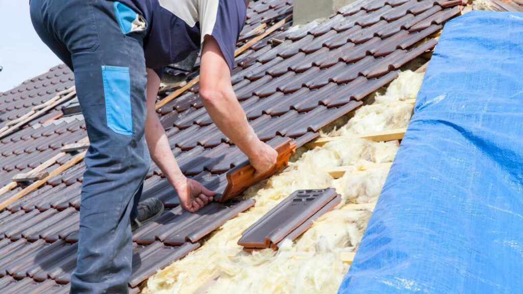 Worker placing new shingles on roof